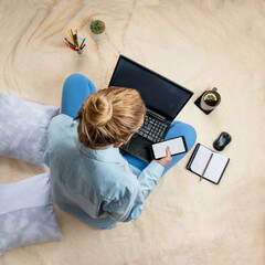 a woman holds a laptop and a smartphone in her hands while sitting on a soft blanket at home.
freelancing remote work concept. laptop, smartphone and notebook.at home
