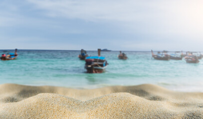 Fototapeta na wymiar Sand beach seaside vacation on daylight with blurred traditional boats on sea on blue sky background