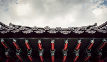 Part of roof of korean house. Symmetric shot of pavilion in front of cloudy sky