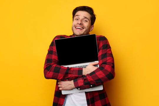 Win Concept. Excited man hugging laptop at studio
