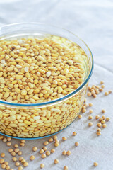 soaked soy bean or soya bean in a glass bowl on fabric background