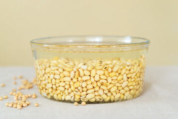 soaked soy bean or soya bean in a glass bowl on fabric background