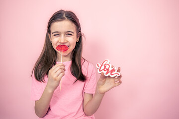 Funny little girl with a lip-shaped lollipop in her hands, copy space.