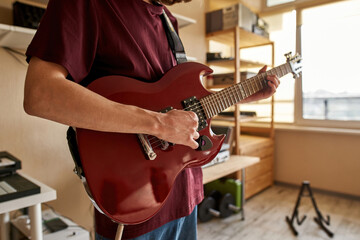 Partial of man playing electric guitar at home