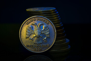 Russian Ruble Coins with falling Stack. Ukrainian flag colors illuminating. Ukraine war sanctions...