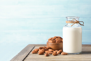 Almond milk with almond nuts on wooden table.