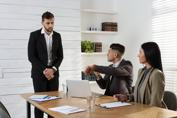 Businessman scolding employee for being late on meeting in office