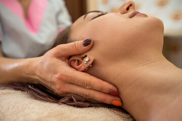 Beautiful girl doing a rejuvenating facial massage in the aroma room