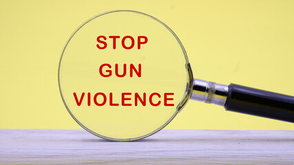 STOP GUN VIOLENCE inscription on a yellow background through a magnifying glass