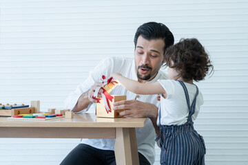Young Caucasian father with beard and little cute daughter are opening gift box together with...