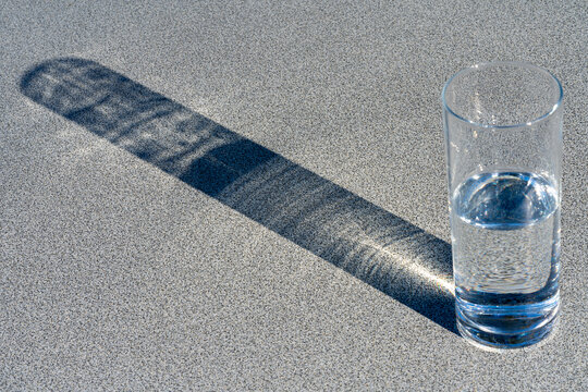 Halbvolles (halbleeres) Wasserglas mit durchscheinender Sonne