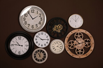 Collection of stylish clocks on brown wall