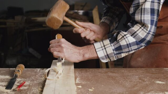 Skilled carpenter carving wood with hammer and chisel. High quality 4k footage