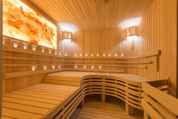 Beautiful interior of a wooden sauna with a rounded bench and an unusual screen glowing with amber...