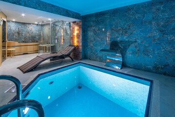 Private swimming pool in blue tones with an artificial waterfall. Entrance to the sauna.