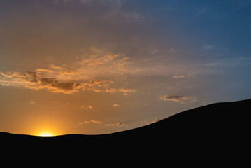 Sunset, silhouette of mountains and hills and sun.