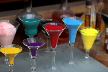 Color powder in glasses. Blue, red, yellow, purple, brown, green pigments. Selected focus.