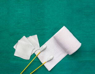 tools include swabs,roll gauze and blood gauze on green surgical dress  for clean wound with copy space