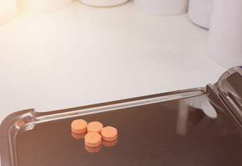 four orange medical tablets on half counting drug tray for drugstore