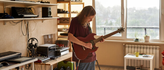 Caucasian musician playing electric guitar at home