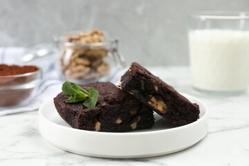 Delicious brownies with nuts and mint on white marble table