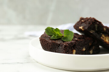 Delicious brownies with nuts and mint on white marble table, closeup. Space for text