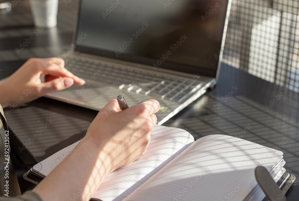 Aufkleber hands closeup taking notes, writing in business planner at laptop computer at desk.