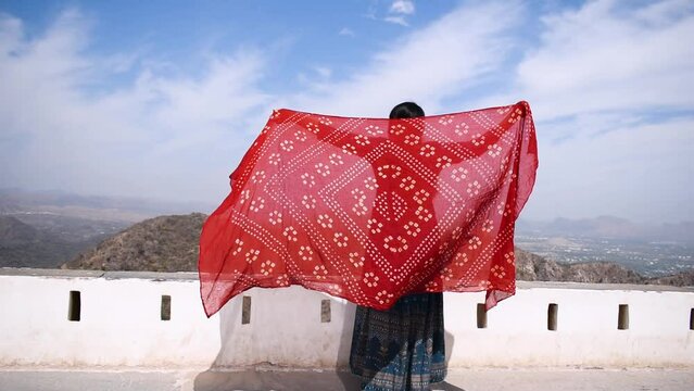 Young Indian girl standing with holding Bandhani Dupatta at Sajjangarh fort, Rajasthan, India. Tourist enjoying holiday with Indian culture and history. Indian traditional dupatta