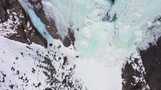 Ice Climbing on Frozen Waterfall, Aerial View. Barskoon Valley, Kyrgyzstan. Drone Flies Backwards and Upwards