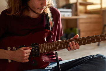 Obscure face of young man playing electric guitar