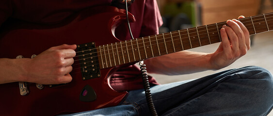 Cropped of man playing chords on electric guitar