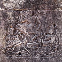 Fototapeta premium Stone-carved bas-relief with dancing apsaras in ancient Khmer temple in Angkor, Siem Reap, Cambodia