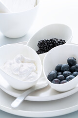 Three bowls with blueberry blackberry and yogurt on white background. Healthy food concept.