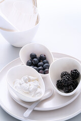 Three bowls with blueberry blackberry and yogurt on white background. Healthy food concept.