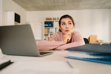 Thoughtful businesswoman, pondering ideas, developing business strategy, looking in distance, using laptop, pensive employee taking break, dreaming or visualizing in office