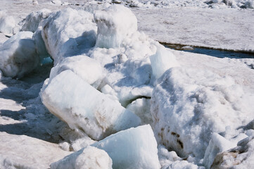 Ice drift on the Amur River. Melting ice floes in spring. A heap of blocks and fragments. Sunny day.