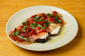 Crostini with goat cheese, prosciutto, sun dried tomatoes and basil