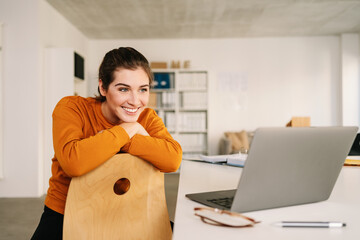 Happy woman in home office looking at laptop