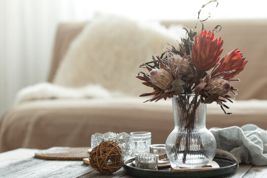 Cozy home composition with candles and protea bouquet.