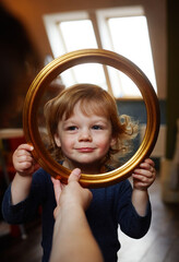 Little happy child looking through a round frame.