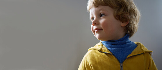 Little Ukrainian child smiling. He is wearing blue and yellow clothes.
