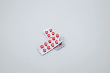 Two packages with red round tablets on a white background. Pills to support the work of the heart. One tablet is missing.