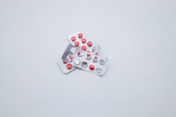 Three packages with red round tablets on a white background. Pills to support the work of the heart. Some pills are missing.