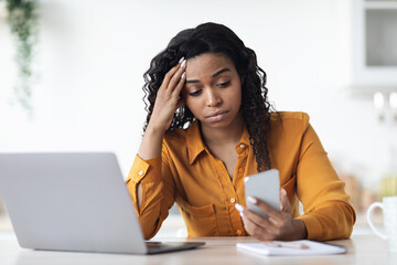 Upset black woman looking at smartphone screen