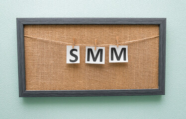 letters smm on white background are written on pieces of paper attached with clothespins to board