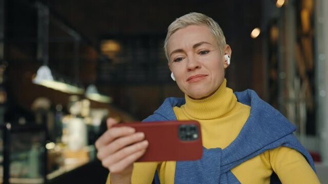 Middle aged woman using mobile for video call at cafe