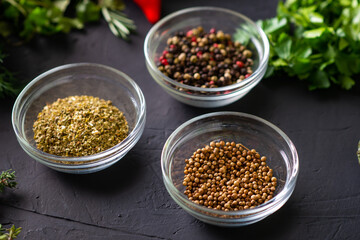 whole coriander and various spices - oregano, pepper. Black background.