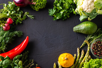 Frame of vegetables on a dark background. Different vegetables around empty space for text....