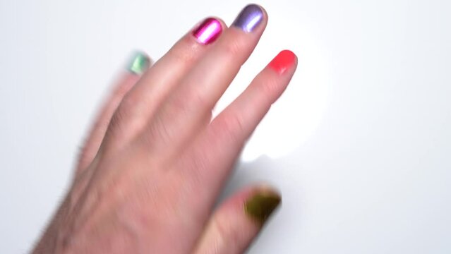 Gay and LGBT man looking at his hand nails work in rainbow colors. Gender fluid or transgender male with coloured fingernails manicure.