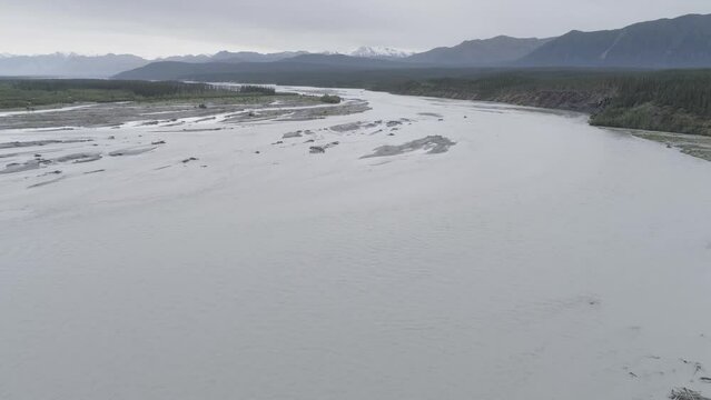Slow backward drone flight over a braiding muddy glacial river in Kluane National Park, Canada